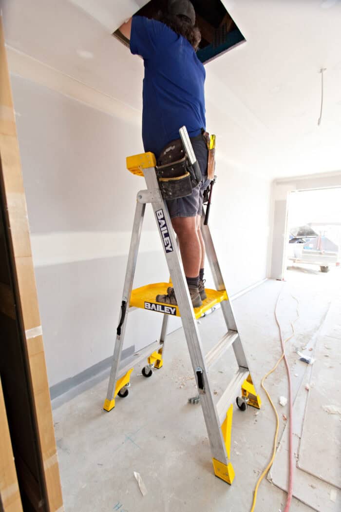 Man standing on Bailey P170 Aluminium Job Station Platform FS13538 with tool belt, reaching manhole