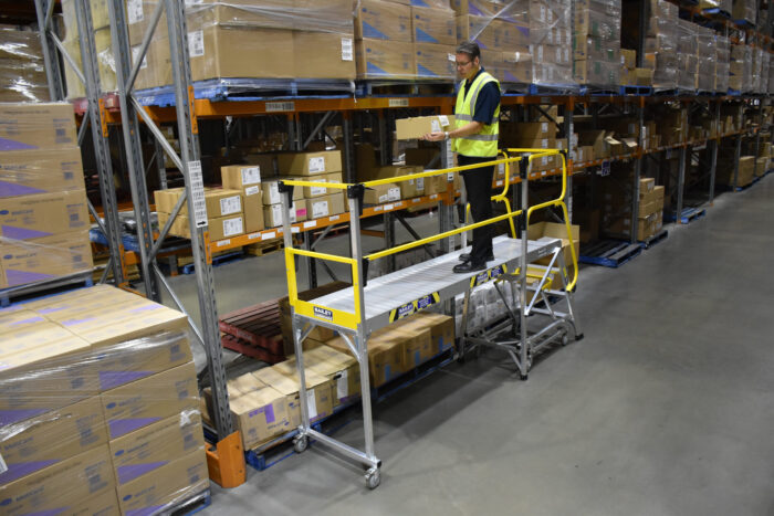 Bailey modular access system, with man standing on 2m platform to access pallet racking in warehouse